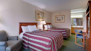 A hotel room with two beds, a chair, a desk, and a mirror.