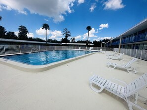 Una piscina con sillas de descanso blancas y una cerca blanca.