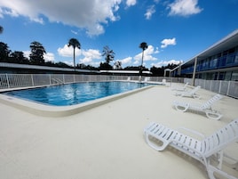 Una piscina con sillas de descanso blancas y una cerca blanca.