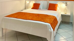 Une chambre d’hôtel avec un lit, des murs blancs et des touches de couleur orange.