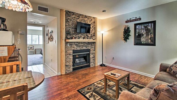 A living room with a stone fireplace, a television mounted above it, and a couch.