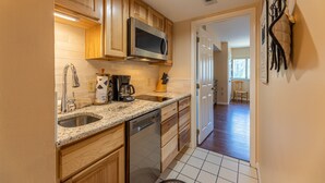 A kitchen with wooden cabinets, a stainless steel microwave, a dishwasher, and a coffee maker.