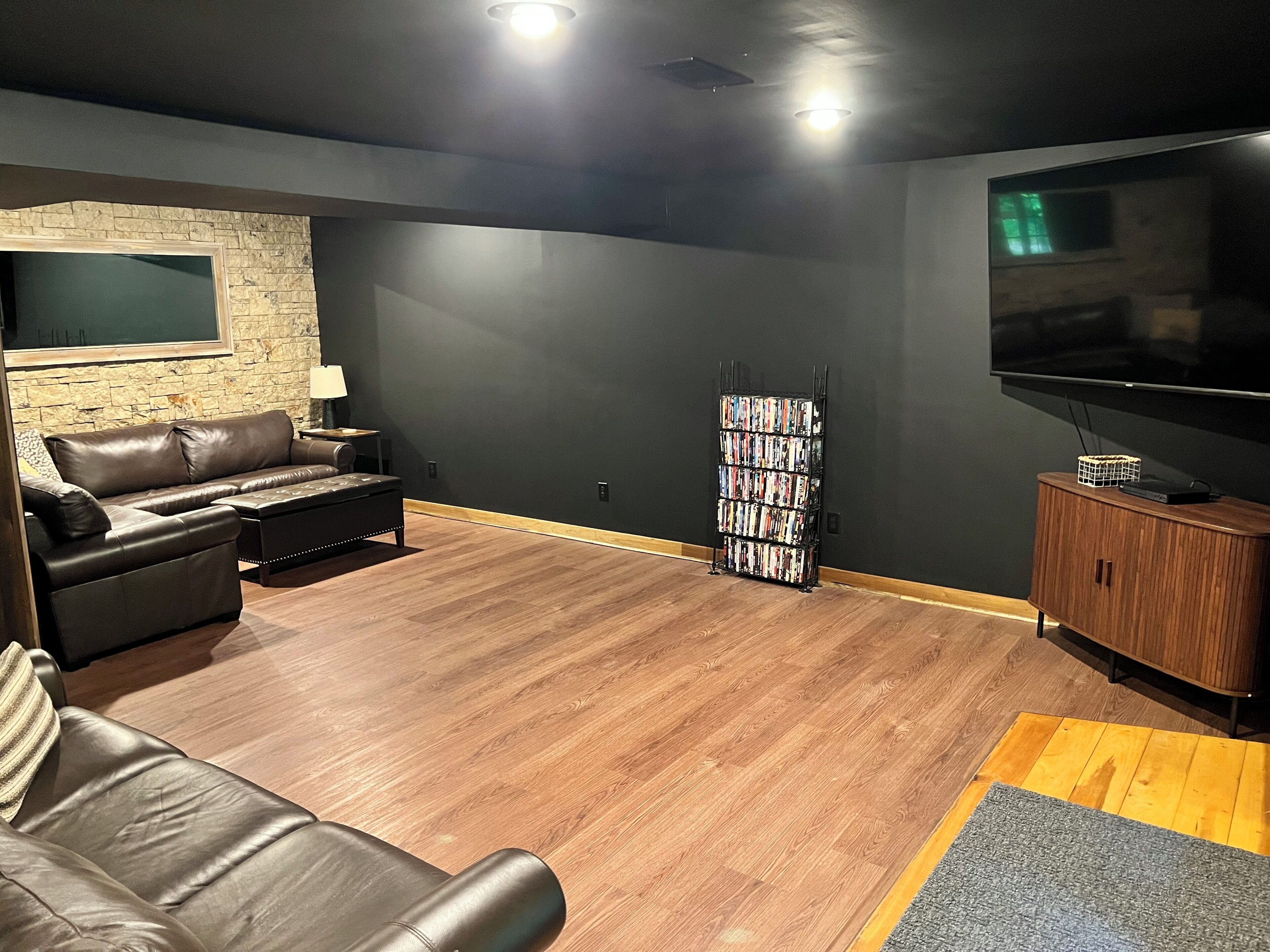 Un salon moderne avec un canapé en cuir, un téléviseur à écran plat, une bibliothèque et un meuble en bois.