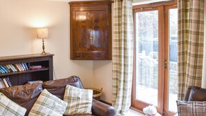 A cozy living room with a leather sofa, a wooden cabinet, and a window with plaid curtains. - 3 bedroom accommodation in Sockbridge, near Penrith (Sockbridge, near Penrith)