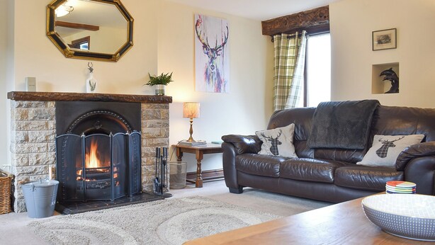 A cozy living room with a fireplace, a leather sofa, and a dining table. - 3 bedroom accommodation in Sockbridge, near Penrith (Sockbridge, near Penrith)