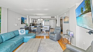 A modern living room with a sectional sofa, a grey armchair, and a dining area with a table and chairs.