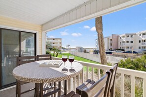 Un balcon avec une table, deux chaises et deux verres à vin.