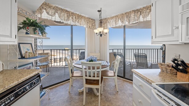 Una cocina con comedor, ventanas amplias y vista al océano.