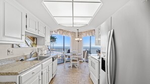 Una cocina moderna con armarios blancos, encimera de granito y vista al exterior.