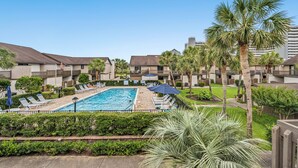 A pool area with lounge chairs and umbrellas, surrounded by palm trees and a clear sky. - Sea Gate Villas 20 2 Bedroom Condo with Outdoor Pool! (Myrtle Beach)