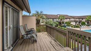 A wooden deck with lounge chairs, a pool, and a view of other buildings. - Sea Gate Villas 20 2 Bedroom Condo with Outdoor Pool! (Myrtle Beach)
