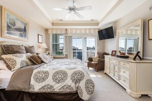 Ein Schlafzimmer mit Bett, Kommode, Fernseher und Balkon.