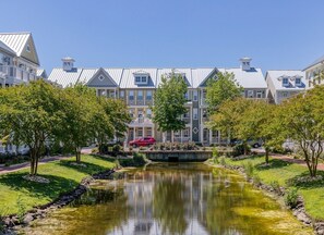 Una zona residencial con un estanque, casas con tejados a dos aguas y un puente.