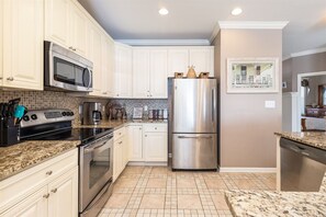 Una cocina con armarios blancos, electrodomésticos de acero inoxidable y salpicadero de azulejos.