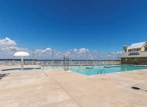 Une piscine extérieure, avec un ciel dégagé, une structure en forme de dôme blanc et un bâtiment doté d’un balcon.
