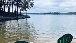 Two green Adirondack chairs on a sandy beach with a calm lake and trees in the background. - Dock. Waterslide. Beach. Firepit, Gazebo, 500ft water frontage. Views. Sleep 18. (Equality)