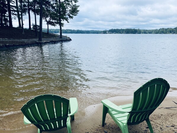 Two green Adirondack chairs on a sandy beach with a calm lake and trees in the background. - Dock. Waterslide. Beach. Firepit, Gazebo, 500ft water frontage. Views. Sleep 18. (Equality)