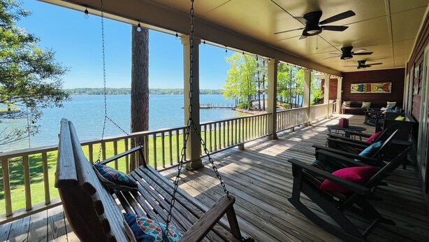 A covered deck with a view of a lake, wooden furniture, and ceiling fans. - Dock. Waterslide. Beach. Firepit, Gazebo, 500ft water frontage. Views. Sleep 18. (Equality)