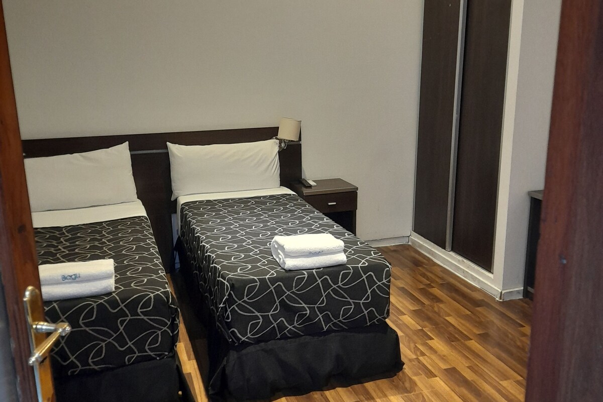 A hotel room with two beds, a wardrobe, and a wooden floor.