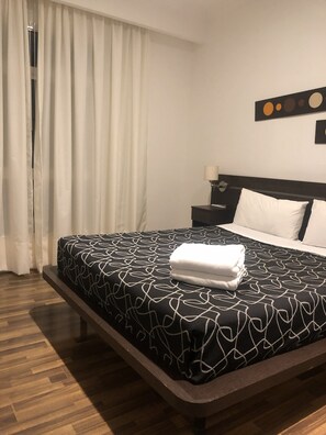 A hotel room with a bed, a nightstand, a lamp, and a window with curtains. - Bagu Buenos Aires (Buenos Aires)