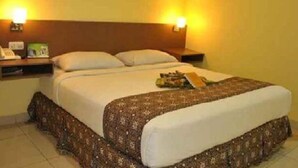 A hotel room with a bed, two bedside tables, and wall-mounted lamps. - Bunda Hotel Bukittinggi (Bukittinggi)
