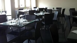 A dining area with tables and chairs, some with condiments and napkins. - Bunda Hotel Bukittinggi (Bukittinggi)