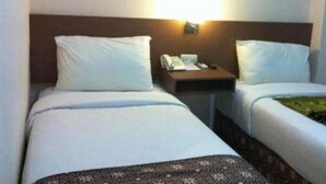 A hotel room with two single beds, a bedside table with a phone, and a wall-mounted light. - Bunda Hotel Bukittinggi (Bukittinggi)