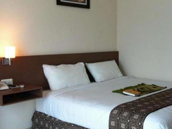 A hotel room with a bed, a nightstand with a lamp, and a framed picture on the wall.