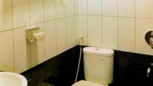 A bathroom with white tiles, a toilet, and a paper towel dispenser. - Bunda Hotel Bukittinggi (Bukittinggi)
