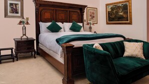 Un dormitorio con una cama de madera, almohadas verdes, una silla verde y dos mesitas de noche con lámparas.