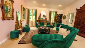Un salón amplio con un sofá de terciopelo verde, una mesa de centro redonda y un espejo grande.