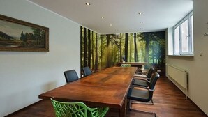 A conference room with a long wooden table, black chairs, and a forest-themed wall mural. - Dormero Hotel München-kirchheim Messe (Kirchheim by Munich)