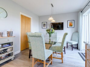 A modern dining area with patterned chairs, a glass table, and a vase of flowers. - 4 bedroom accommodation in Amble, near Morpeth (Amble, near Morpeth)