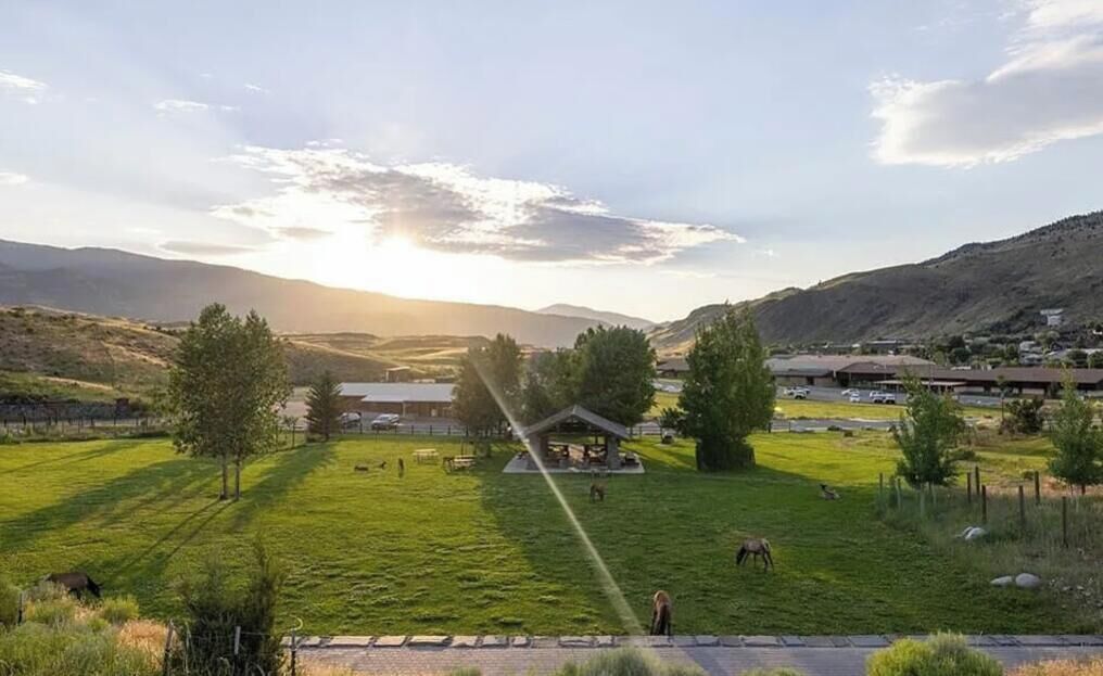 Ländliche Landschaft mit einem Pavillon, offenen Feldern und sanften Hügeln in der Ferne.