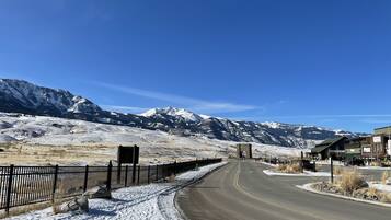 A road curving through a snowy landscape with mountains in the background and a building with a sign 'YELLOWPHONE FOY' on the right.