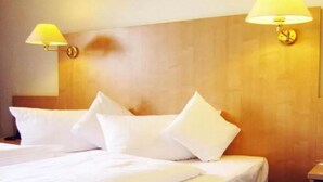 A hotel room with a wooden headboard, two bedside lamps, and multiple pillows. - Motel Frankfurt by Advena (Frankfurt)