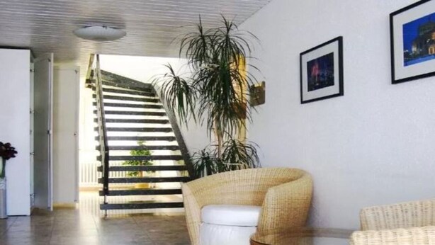 A modern interior with a staircase leading to an outdoor area, wicker furniture, and framed pictures on the wall. - Motel Frankfurt by Advena (Frankfurt)