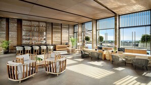 Un vestíbulo espacioso con zona de bar, asientos y amplias ventanas con vistas al exterior.