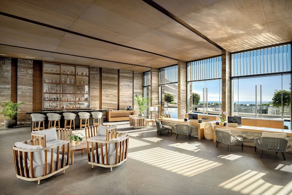 A spacious lobby with a bar area, seating arrangements, and large windows offering views of the outdoors.
