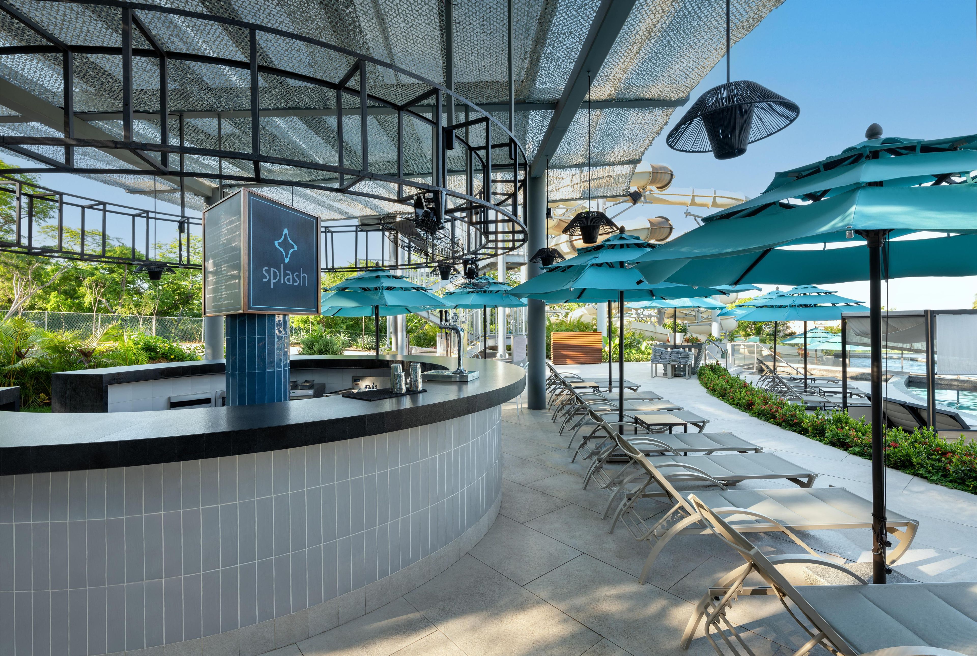 A modern outdoor bar area with a counter, seating, and umbrellas.