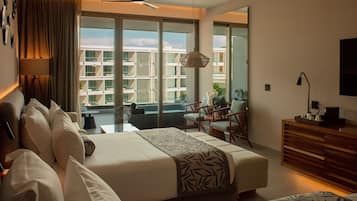 Habitación de hotel con una cama grande, un escritorio, una silla y un balcón con vistas a otros edificios.