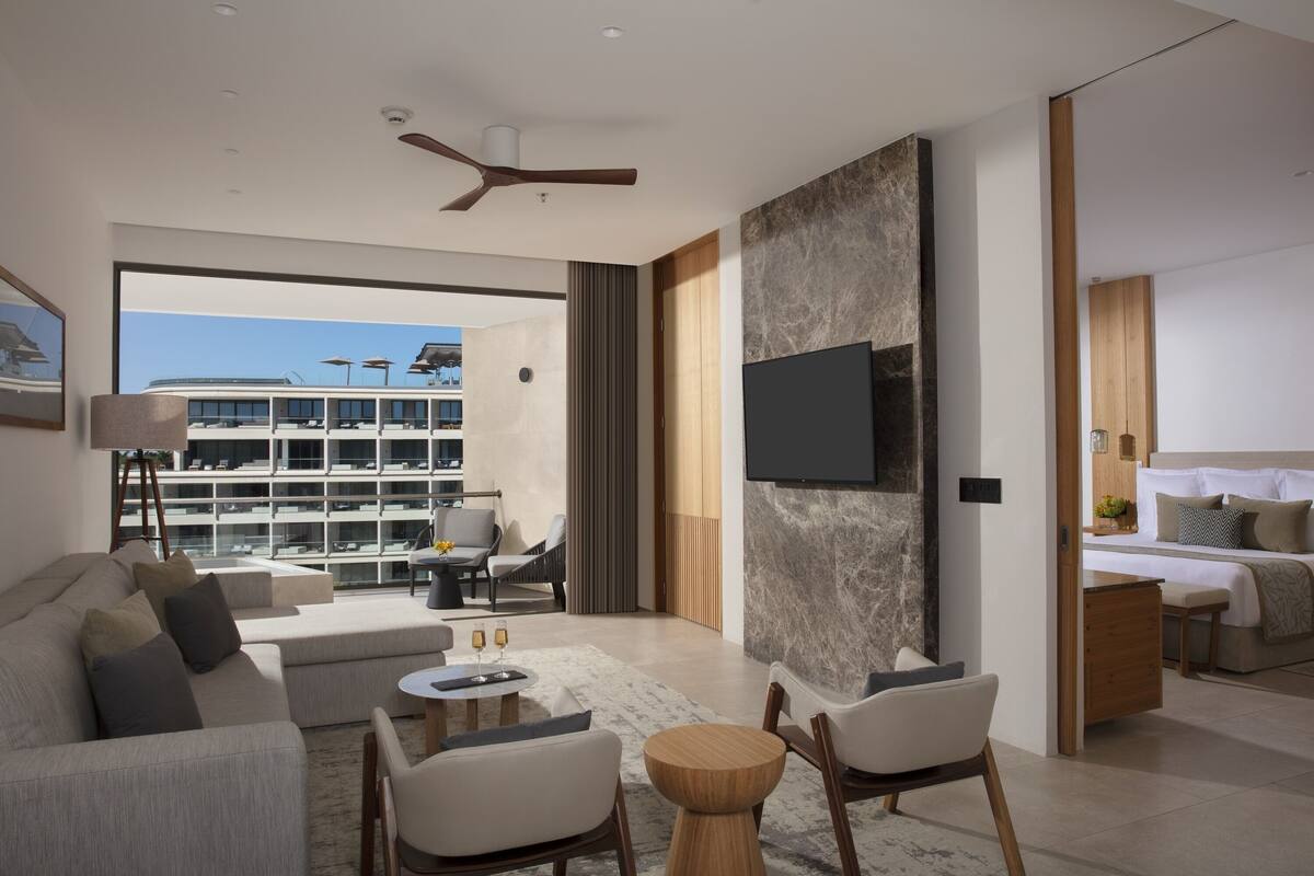A modern living room with a sofa, chairs, a coffee table, and a TV mounted on the wall.
