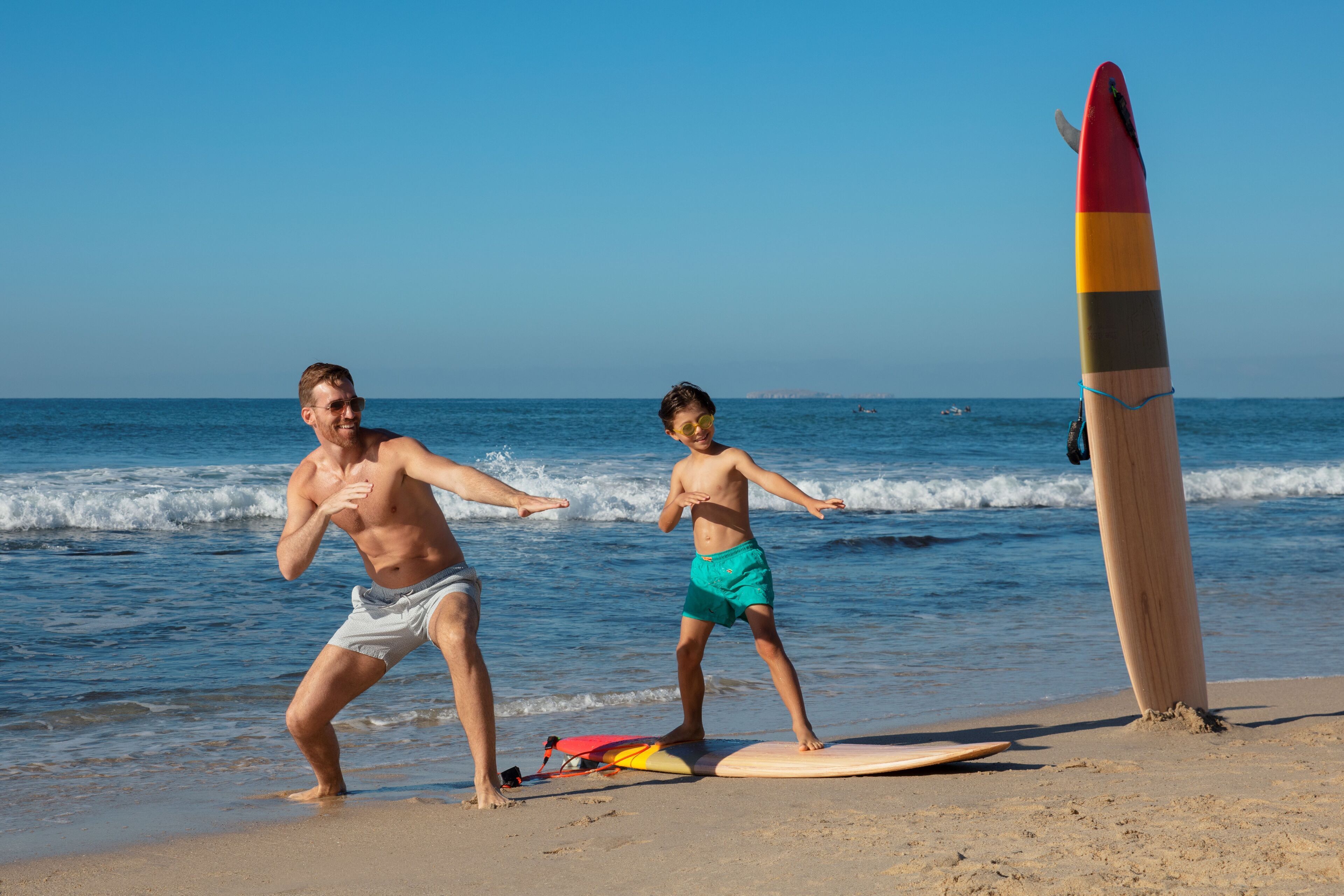 Deux personnes s’entraînent sur une plage, avec des planches de surf et un support à planches.