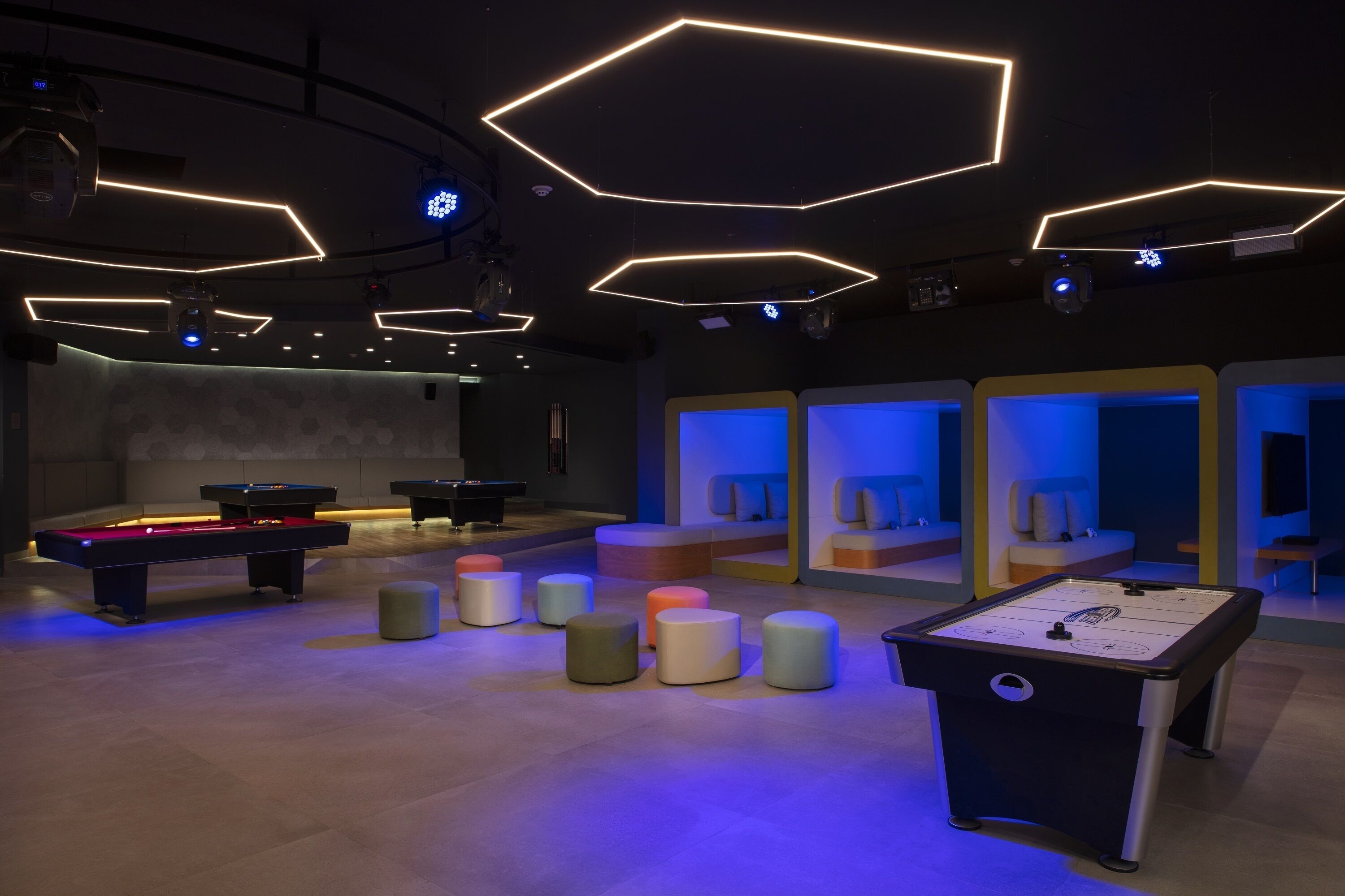 A modern indoor recreational area with pool tables, foosball tables, and seating areas.