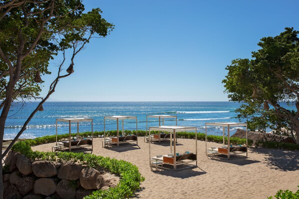 A beachside resort with outdoor seating areas and a view of the ocean.