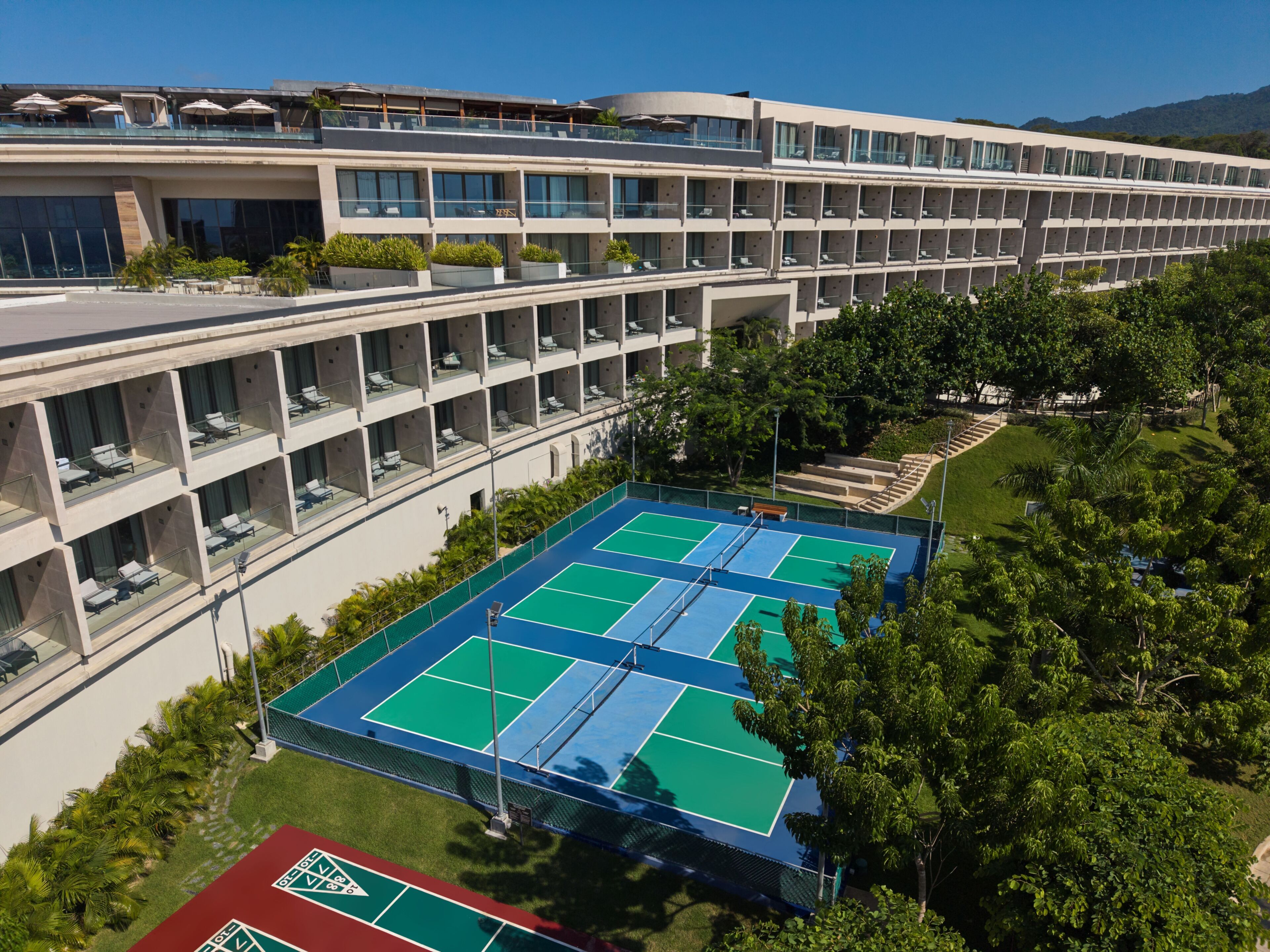 A multi-story hotel with a tennis court and outdoor seating area.