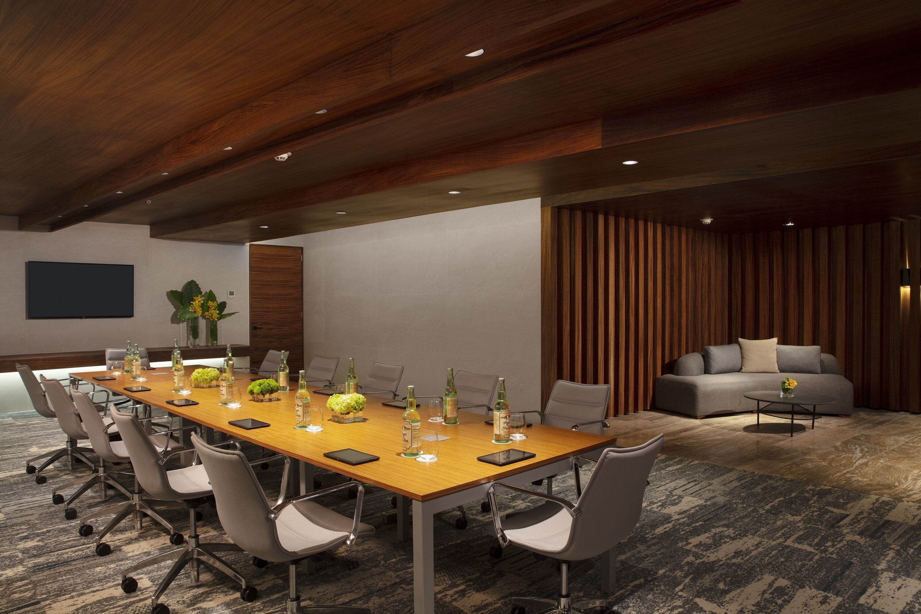 A conference room with a long table, chairs, and a sofa.