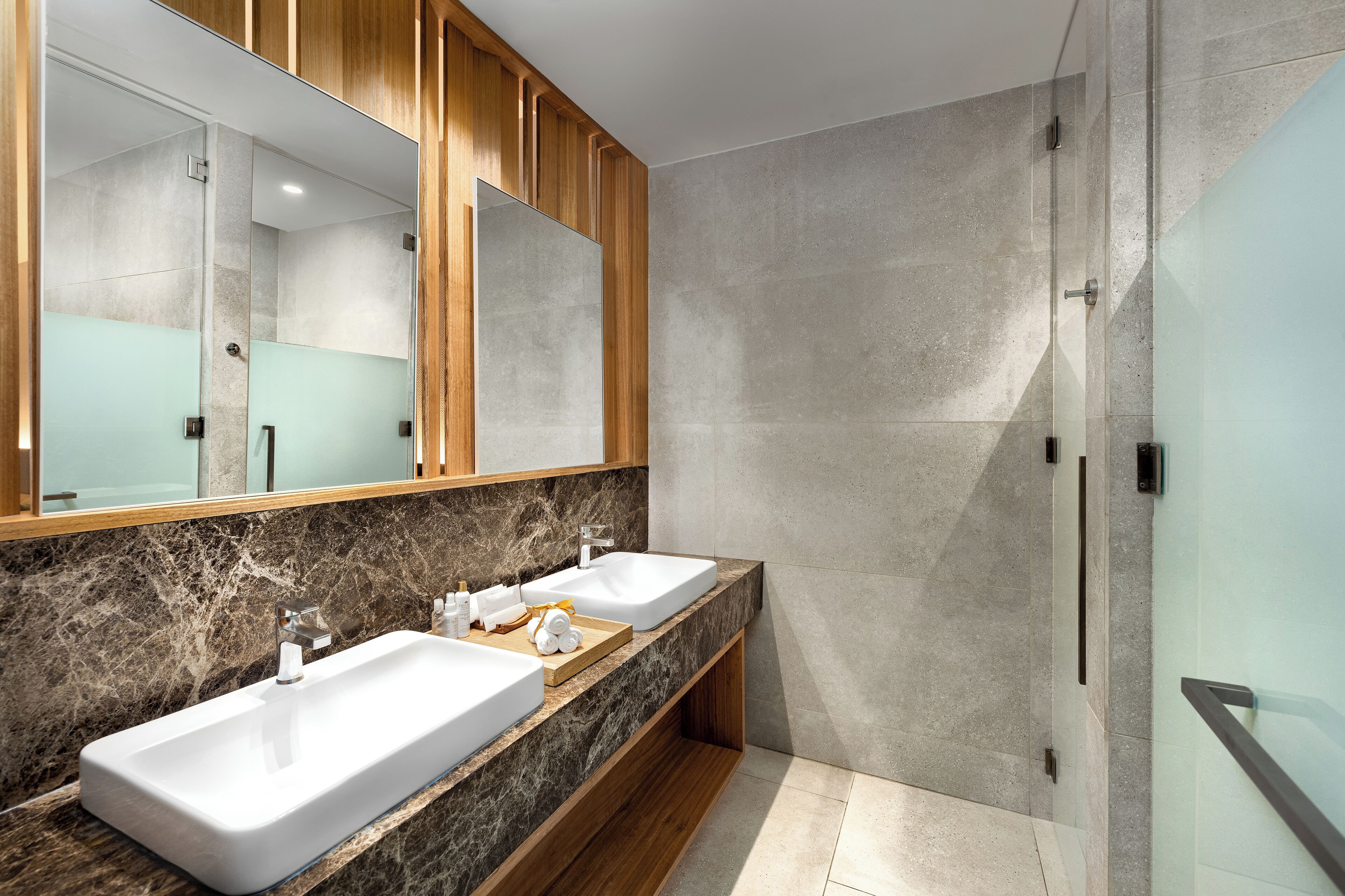 A modern bathroom with two sinks, a large mirror, and a shower area.