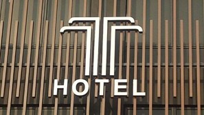 A hotel sign with vertical wooden slats and a large, stylized 'T' logo above the word 'HOTEL'. - T Hotel (Johor Bahru)