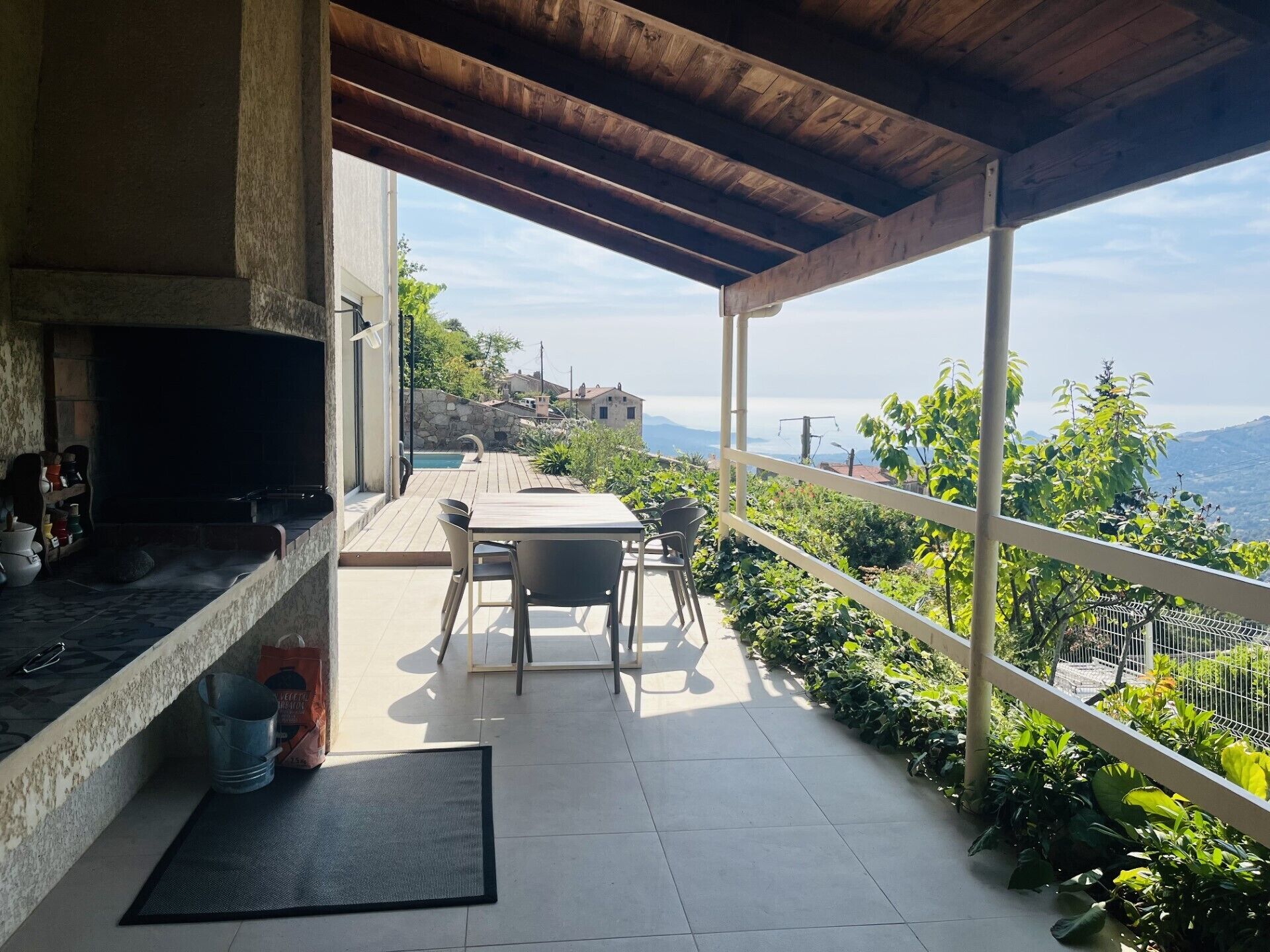 A covered patio with a table and chairs, a fireplace, and a view of a mountainous landscape.